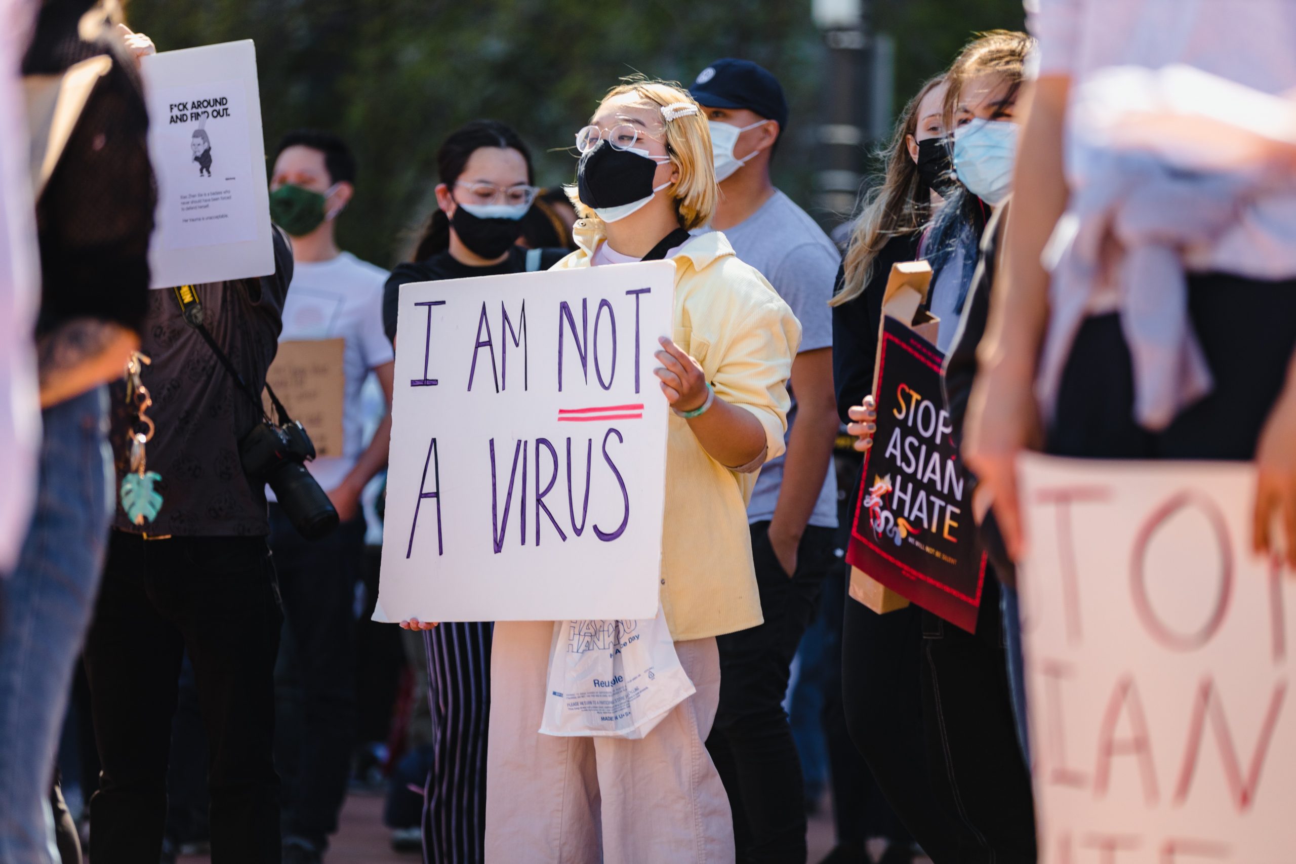 crowd of people holding signs protesting Anti-Asian hate